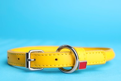 Yellow leather dog collar on light blue background, closeup. Space for text