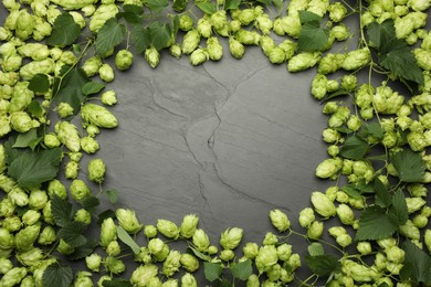 Photo of Frame of fresh green hops and leaves on black table, flat lay. Space for text