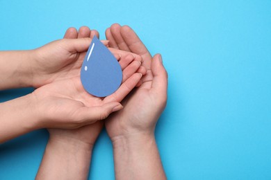 Photo of Save Water concept. Man and woman holding paper drop on light blue background, top view with space for text