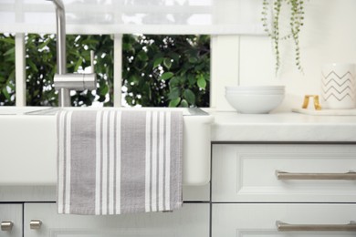 Clean towel hanging on white sink in kitchen