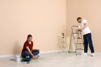 Happy couple with painting tools in apartment during repair