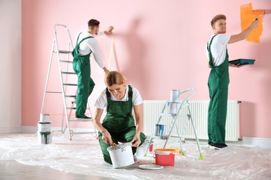 Team of professional decorators painting wall indoors. Home repair service