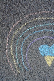Photo of Rainbow with heart drawn by blue and yellow chalk on asphalt, top view