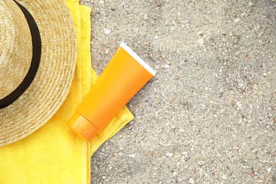 Flat lay composition with tube of sun protection body cream on sand beach, space for text