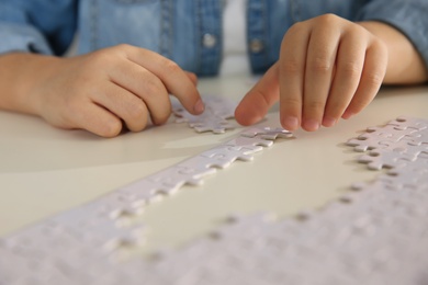 Little girl playing with puzzles at table, closeup