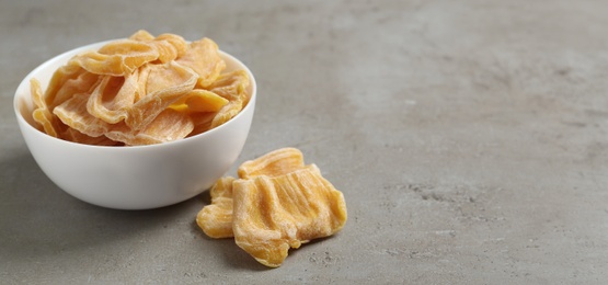 Delicious dried jackfruit slices on light grey table. Space for text