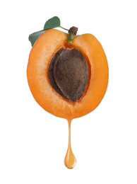 Apricot kernel oil dripping from fresh fruit half on white background