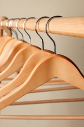 Clothes hangers on wooden rack against beige background, closeup
