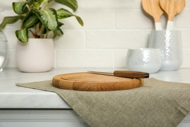 Clean towel, wooden cutting board and knife on countertop in kitchen