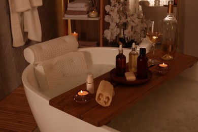 Tub with soft bath pillow, toiletries and wine indoors