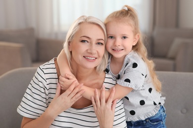 Portrait of mature woman and her granddaughter on sofa in living room