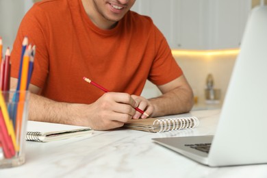 Man drawing in notebook at online lesson indoors, closeup. Distance learning