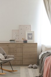 Photo of Modern chest of drawers in beautiful bedroom. Interior design