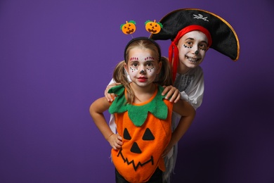 Cute little kids wearing Halloween costumes on purple background