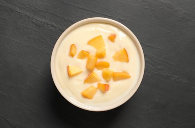 Delicious yogurt with fresh peach on black table, top view