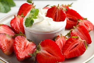 Delicious strawberries with whipped cream on plate, closeup