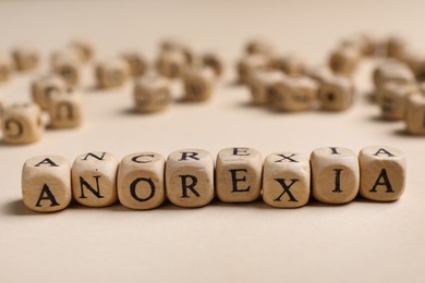 Word Anorexia made of wooden cubes with letters on beige table