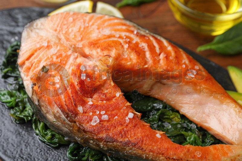 Tasty salmon with spinach served on table, closeup