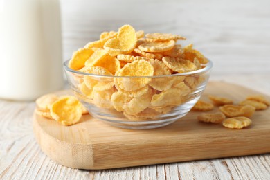 Photo of Glass bowl of tasty crispy corn flakes on white wooden table