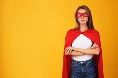 Confident woman wearing superhero cape and mask on yellow background. Space for text