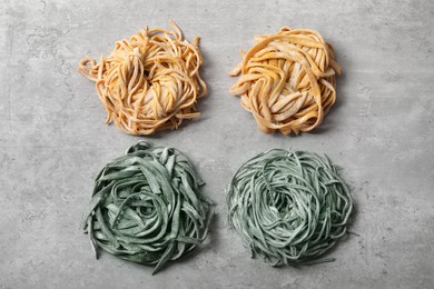 Photo of Rolled pasta painted with food colorings on light grey table, flat lay