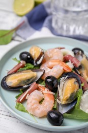 Photo of Plate of delicious salad with seafood on white wooden table, closeup