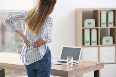 Woman suffering from back pain in office. Symptom of bad posture