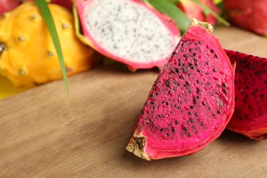 Delicious cut red pitahaya fruit on wooden board, closeup. Space for text