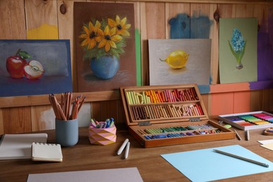 Blank sheets of paper, colorful chalk pastels and drawing pencils on wooden table indoors. Modern artist's workplace
