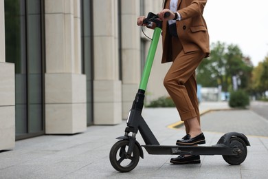 Businesswoman with modern electric kick scooter on city street, closeup. Space for text