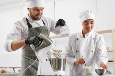 Photo of Pastry chefs preparing dough in mixer at kitchen table