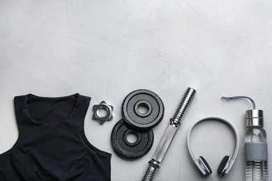 Flat lay composition with sportswear and equipment on light grey table, space for text. Gym workout