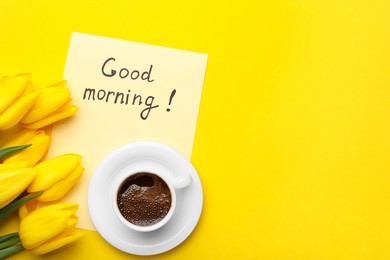 Photo of Cup of aromatic coffee, beautiful tulips and Good Morning note on yellow background, flat lay. Space for text