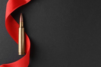 Bullet and red ribbon on black background, top view. Space for text