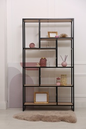 Stylish shelving unit with different decor near white wall indoors. Interior design