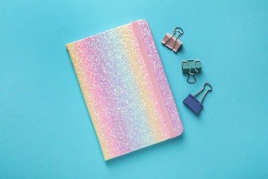 New stylish planner and paper clips on light blue background, flat lay