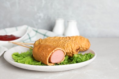 Delicious corn dogs with lettuce on light table