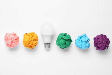 Creative flat lay composition with lightbulb and colorful paper balls on white background. Idea concept