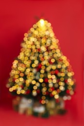 Blurred view of beautifully decorated Christmas tree on red background