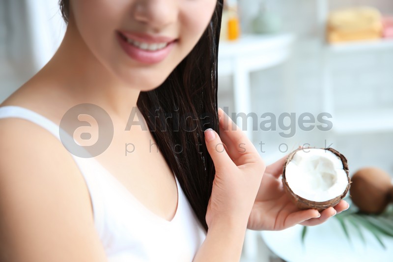 Young woman applying coconut oil onto hair at home