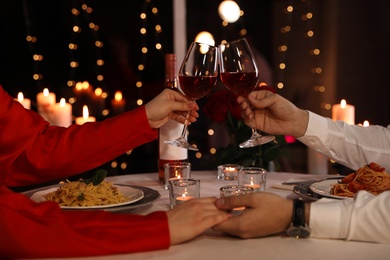 Couple clinking glasses of wine in restaurant, closeup. Romantic dinner