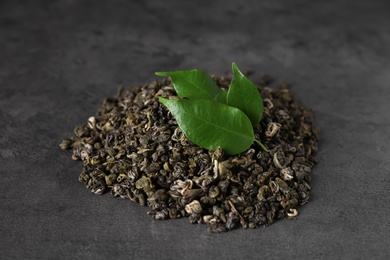Heap of dried green tea leaves on grey table