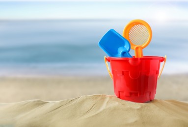 Plastic toy set with shovel on sandy beach near sea, space for text 