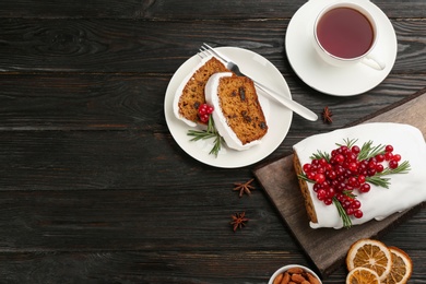 Traditional Christmas cake and cup of tea on black wooden table, flat lay with space for text. Classic recipe
