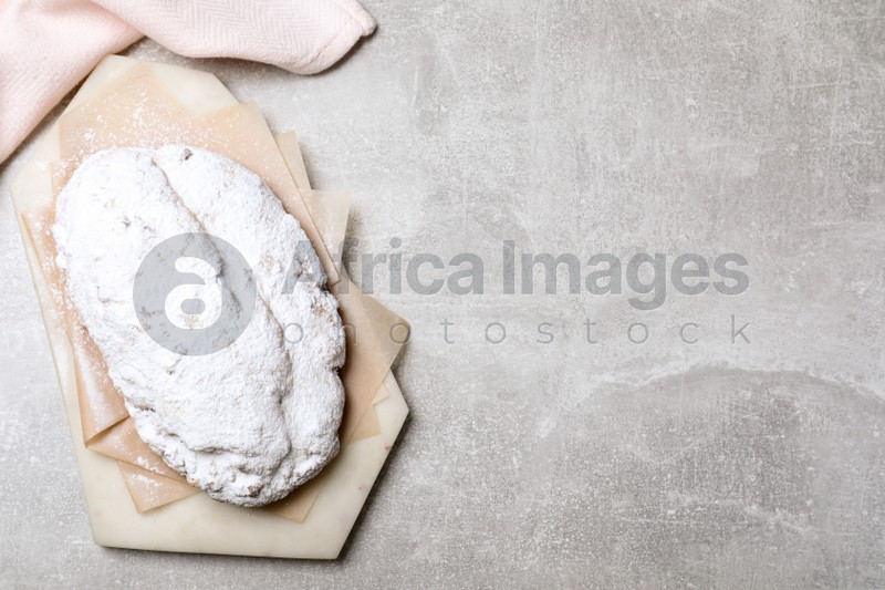 Delicious Stollen sprinkled with powdered sugar on light table, top view. Space for text