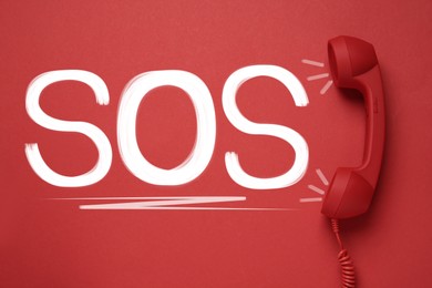Telephone handset on red background, top view. Emergency SOS call