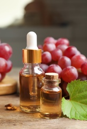 Natural grape seed oil and fresh berries on wooden table. Organic cosmetic