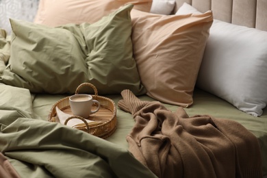 Cup of hot coffee on bed with pistachio linen in room