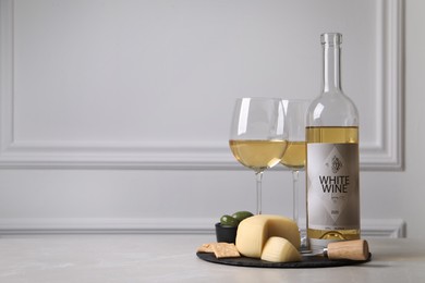 Photo of Bottle of white wine, glasses and crackers with cheese on table, space for text