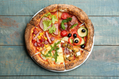Slices of different delicious pizzas on blue wooden table, top view